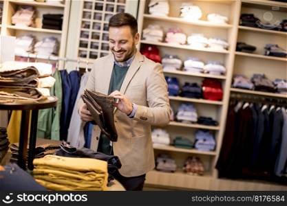 Handsome young man buying trousers in the store