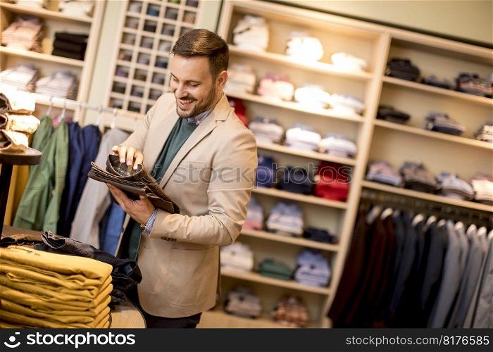 Handsome young man buying trousers in the store