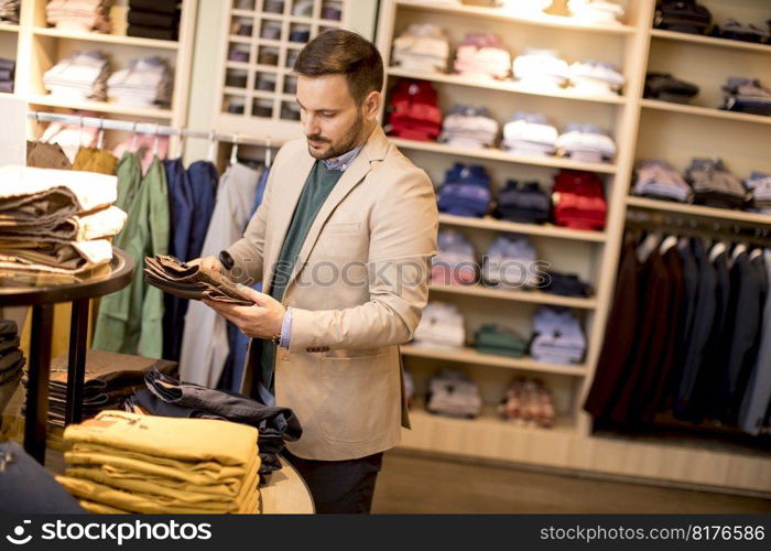 Handsome young man buying trousers in the store