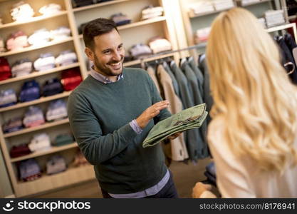 Handsome young man buying trousers with his wife in the store