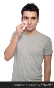 handsome young man cleaning face with cotton swab (isolated on white background)