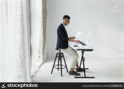 handsome young man coat looking musical sheet playing keyboard