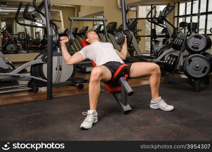 Handsome young man doing Dumbbell Incline Bench Press workout in gym