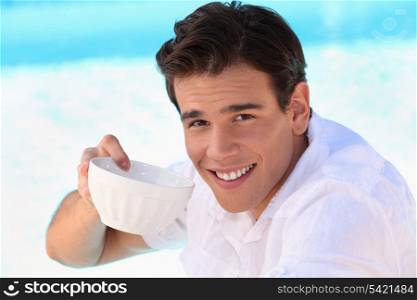 Handsome young man drinking from a bowl