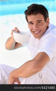 Handsome young man drinking from a china bowl