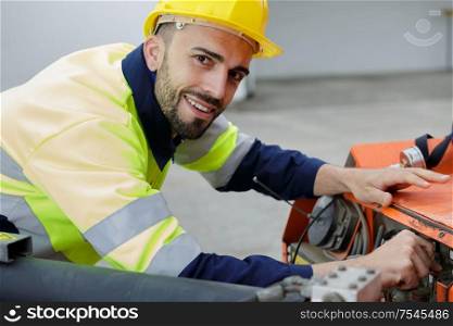 handsome young man electrician wiring cable outdoors