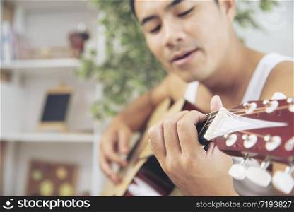 handsome young man holding guitar over shoulder on the beach with the blue sky. Travel Concept