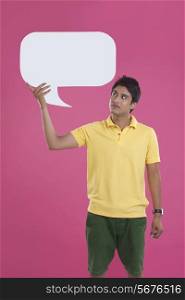 Handsome young man holding speech bubble over pink background