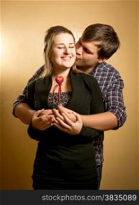 Handsome young man hugging girlfriend from back and kissing in cheek