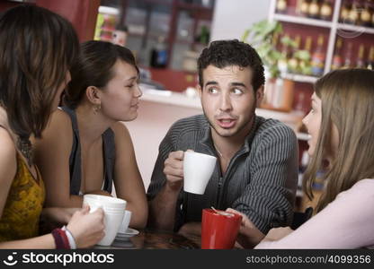 Handsome young man in a coffee house surrounded by pretty women