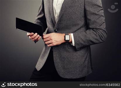 Handsome Young Man in Business Suit. Casual style and Electronic Gadgets. Smart Watches and Digital Tablet