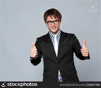 Handsome young man in glasses showing thumbs up