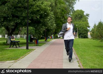 Handsome young man in gray suit walking in the summer park