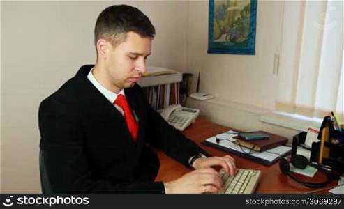 handsome young man in suit and red tie, typing some documents, closeup with slow approach
