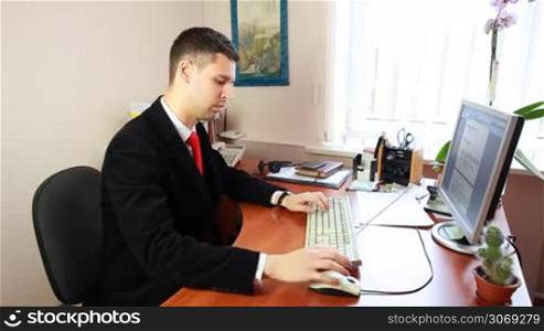 handsome young man in suit with red tie, typing some documents
