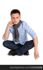 Handsome young man in thoughtful pose sitting with legs crossed, white background.
