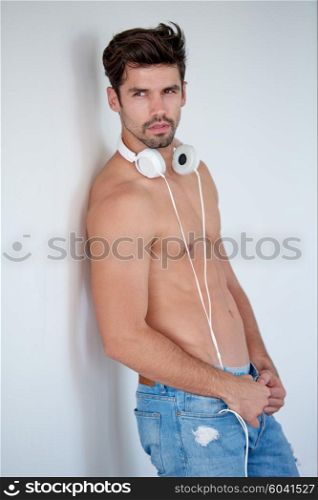 handsome young man listening music on headphones at modern home over white wall and standing on hands