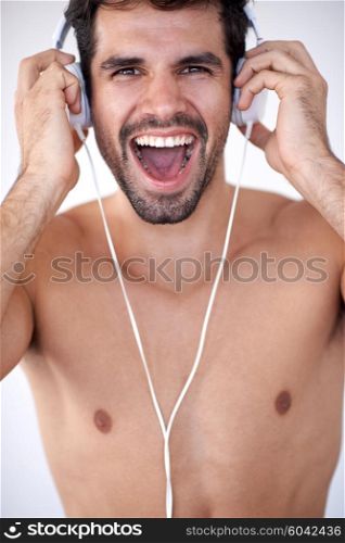 handsome young man listening music on headphones at modern home over white wall and standing on hands
