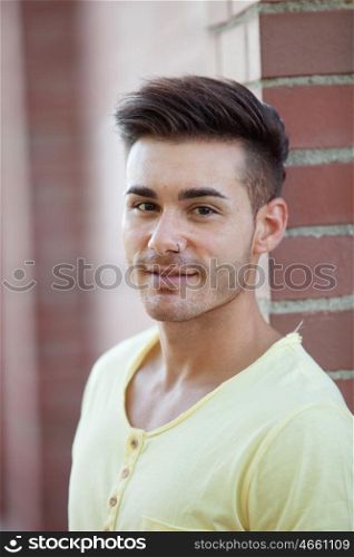 Handsome young man looking at camera leaning against a brick wall