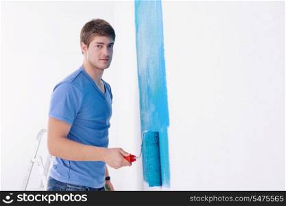 handsome young man paint in blue and green color white wall of new home