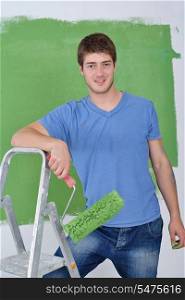 handsome young man paint in blue and green color white wall of new home