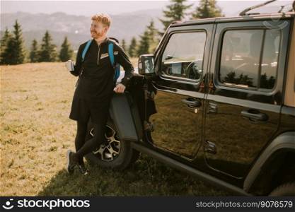 Handsome young man relaxing on a terrain vehicle hood at countryside