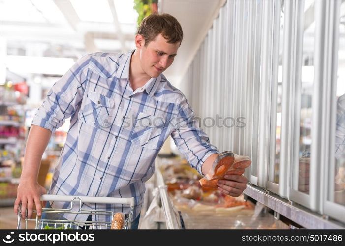 Handsome young man shopping for diary products at a grocery store or supermarket