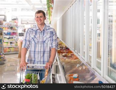 Handsome young man shopping for diary products at a grocery store or supermarket