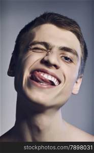 handsome young man showing tongue, closeup portrait