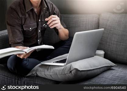 Handsome Young Man Sitting on the Living Room Couch, Casual young man reading documents on sofa at home.