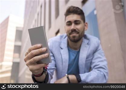 Handsome young man smiling when he is using his mobile phone