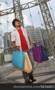 Handsome young man smiling with shopping bags