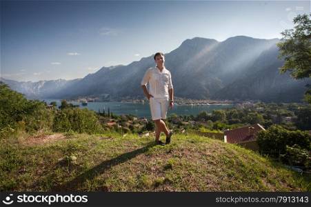 Handsome young man standing on top of high mountain at sunny day