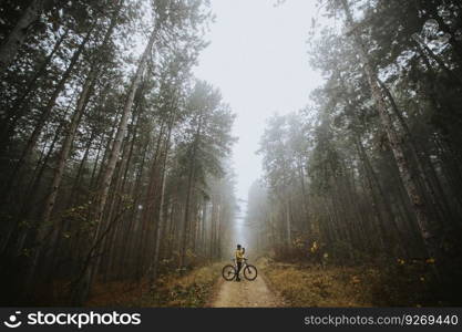 Handsome young man taking a brake during biking through autumn forest