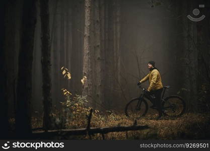 Handsome young man taking a brake during biking through autumn forest