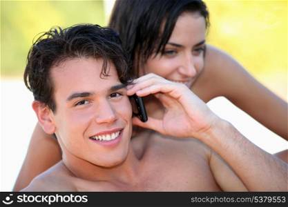 Handsome young man talking on his mobile phone at the beach