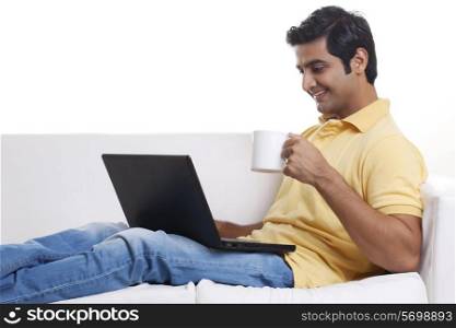 Handsome young man using laptop while having coffee
