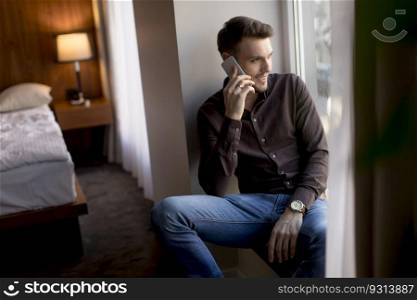 Handsome young man using mobile phone in the room