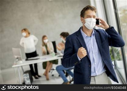 Handsome young man using mobile phone while wear protective masks to prevent corona viruus at office space