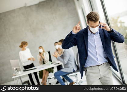 Handsome young man using mobile phone while wear protective masks to prevent corona viruus at office space