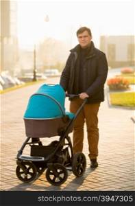 Handsome young man walking with the pram on street