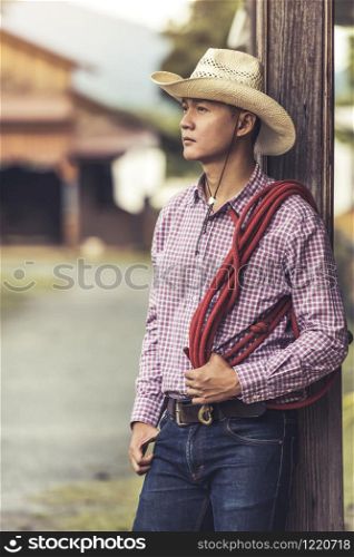Handsome young man wearing cowboy hat scott shirt and blue jean trousers standing thinking