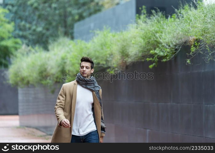 Handsome young man wearing winter clothes walking on the city. Street photo concept.