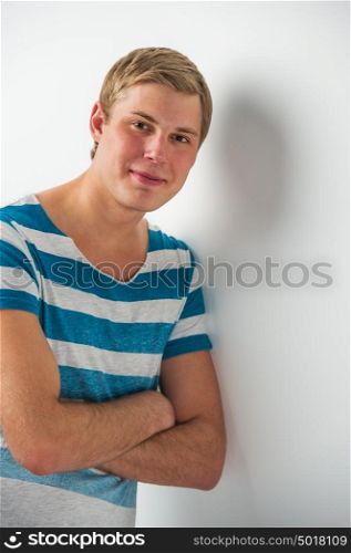 Handsome young man with a charming smile and look leaning on the wall