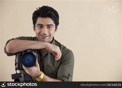 Handsome young man with digital camera over colored background