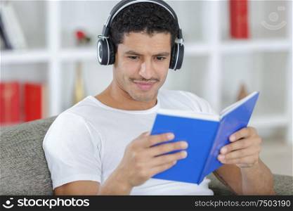 handsome young man with headphones and book