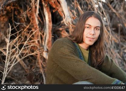 Handsome young man with long hair in an outdoor setting