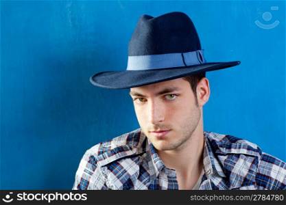 handsome young man with plaid shirt and cowboy hat on blue background