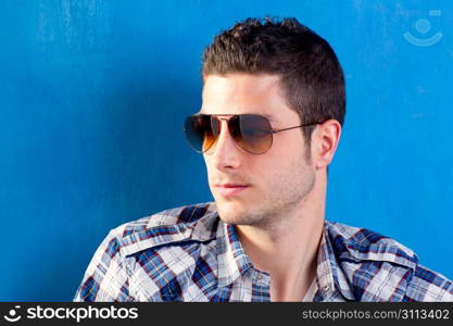 handsome young man with plaid shirt and sunglasses on blue background