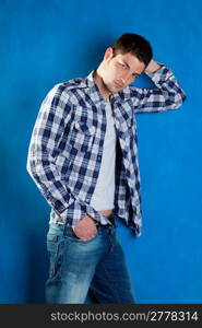 handsome young man with plaid shirt denim jeans in blue background